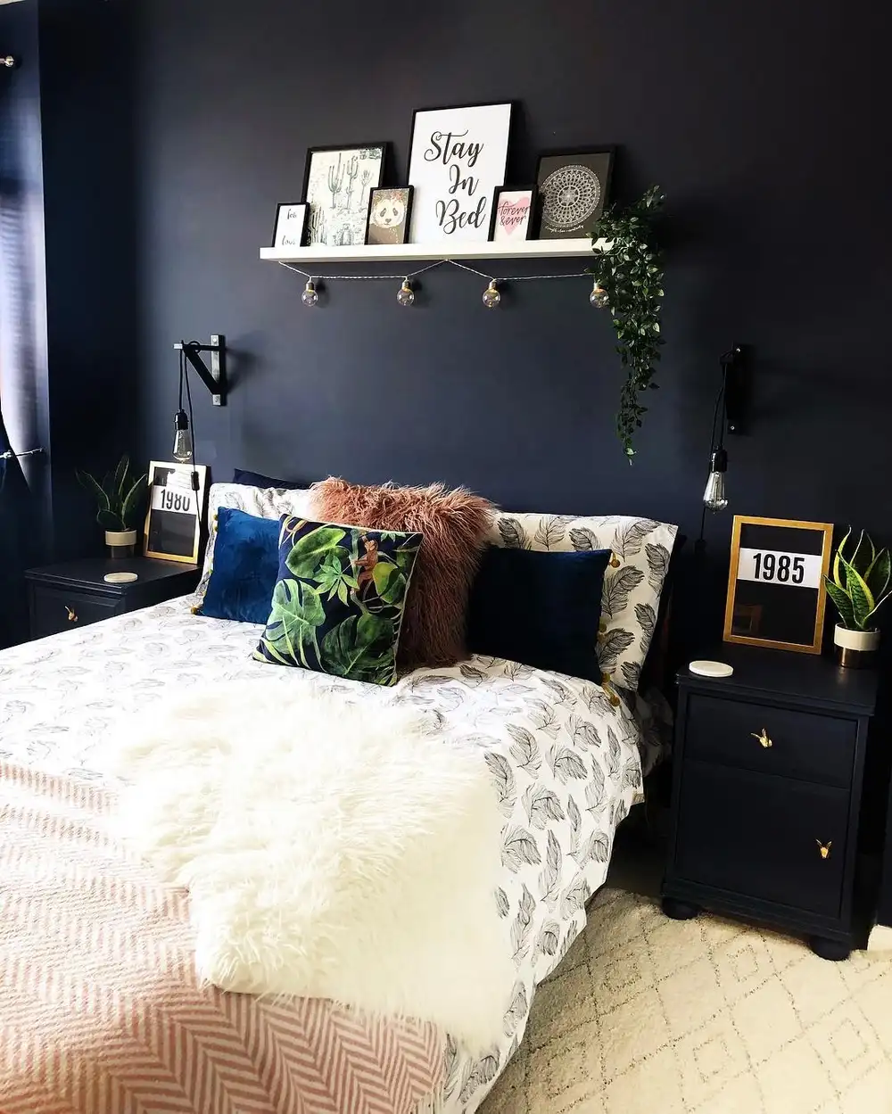 Small bedroom with dark charcoal wall, white bedding and rust and blue accent pillows