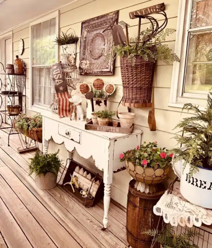 Rustic farmhouse porch with a weathered wooden bench, vintage style wall decor, metal containers, and potted plants