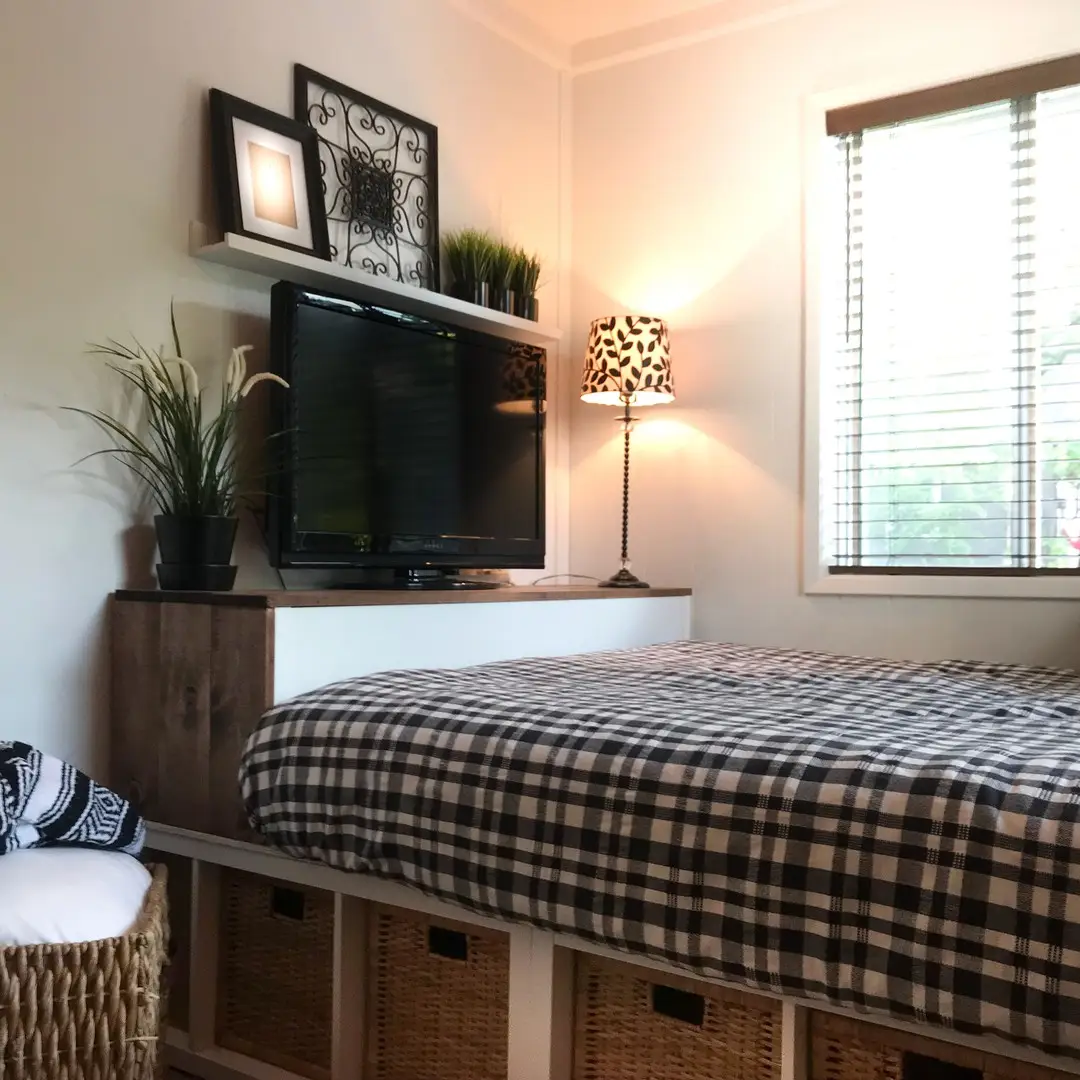 Small bedroom with raised bed and matching woven storage baskets underneath